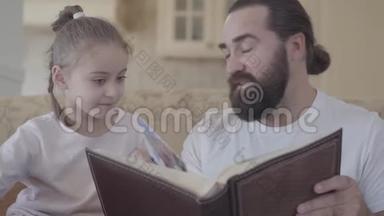 小可爱的女儿和她的父亲坐在客厅里看着相册的肖像，有着美好的回忆和美好的回忆